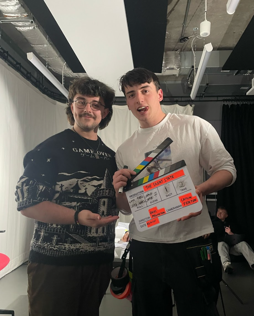 Chris Gray posing with a film collaborator holding a clapperboard